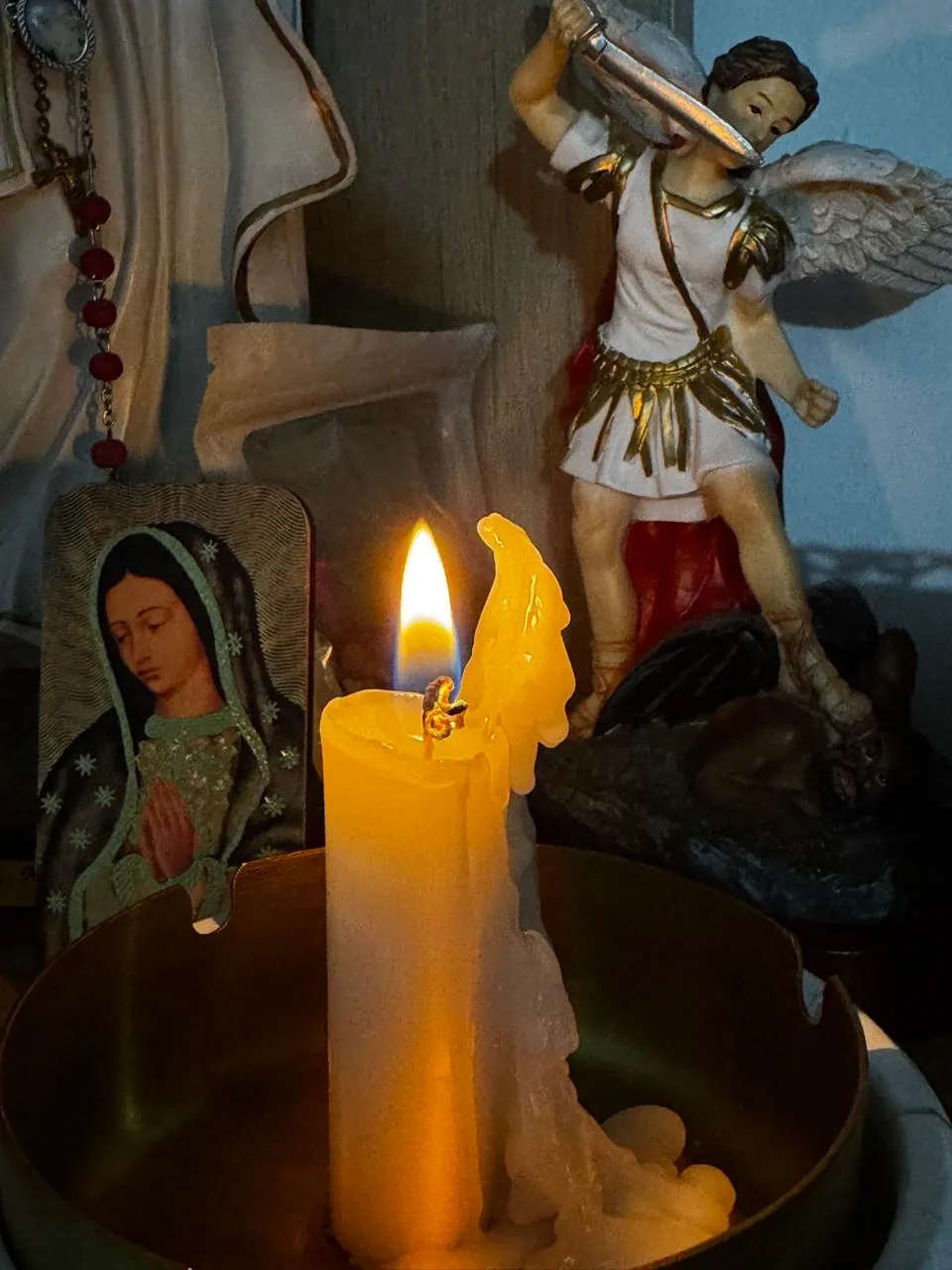 Velón amarillo encendido en un altar con la Virgen de Guadalupe
